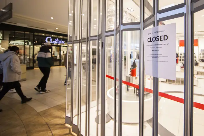 People wearing face masks walk past a closed store at a shopping mall in Brampton, Ontario, Canada, on December 1st, 2020.